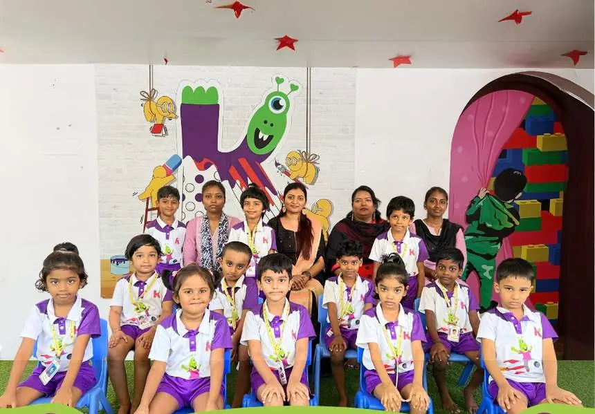 Children and teachers of Kayo International, Chennai, seated in front of the Scrappy wall mural